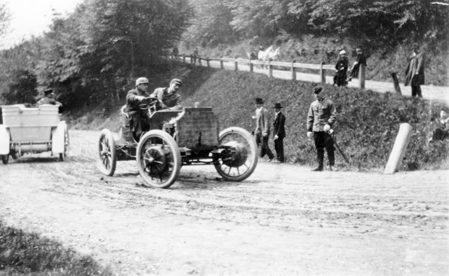 Black and white photo of a Porsche EV hybrid completing a hairpin turn during a hillclimb race.