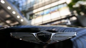 A Genesis logo seen on the front of a car in a dealership.