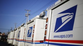 A group of Grumman LLV Postal Service mail trucks are parked.