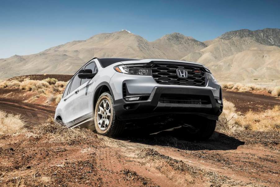 The 2023 Honda Passport TrailSport climbs an off-road obstacle in a desert landscape.