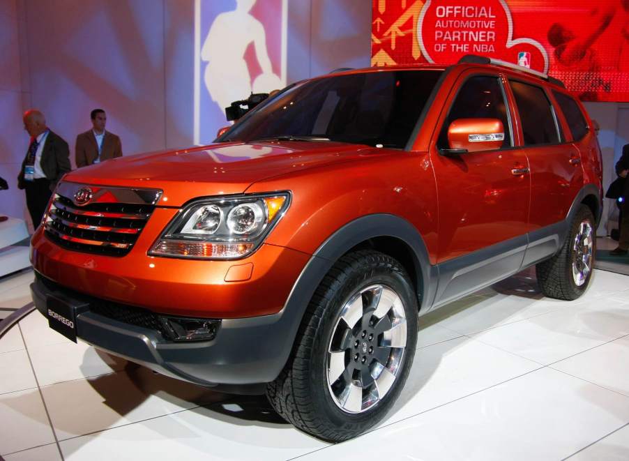 An orange Kia Borrego on display at an auto show.