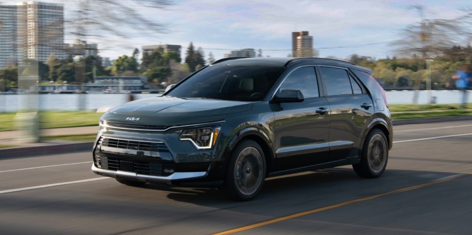 A green 2023 Kia Niro Hybrid small hybrid SUV is driving. 