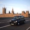 A London Black Taxi driving with the Big Ben in the background