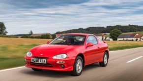 A red Mazda MX-3 driving through the country