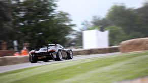 A silver McLaren P1 HDK driving up Goodwood hill