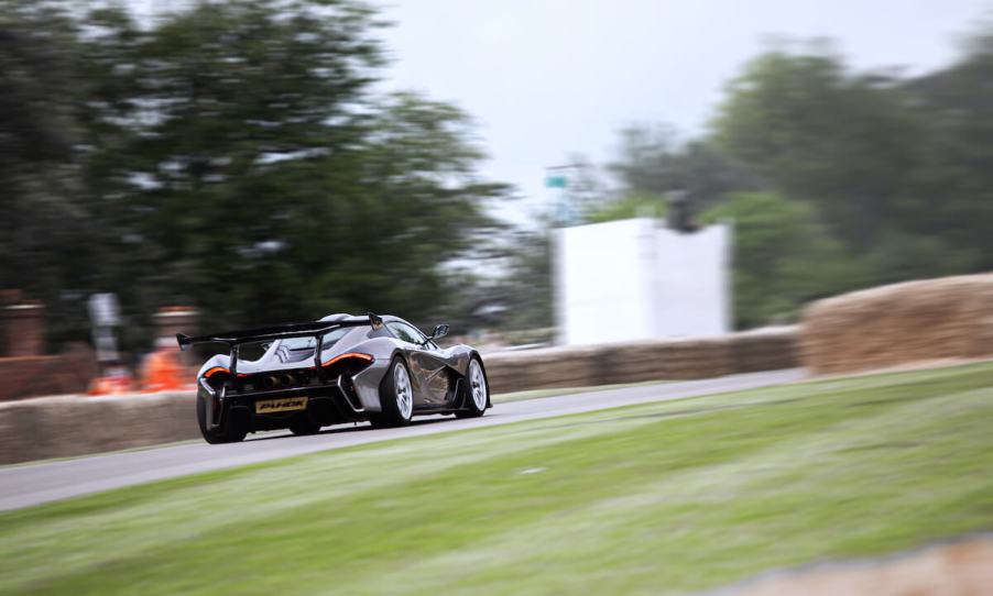 A silver McLaren P1 HDK driving up Goodwood hill