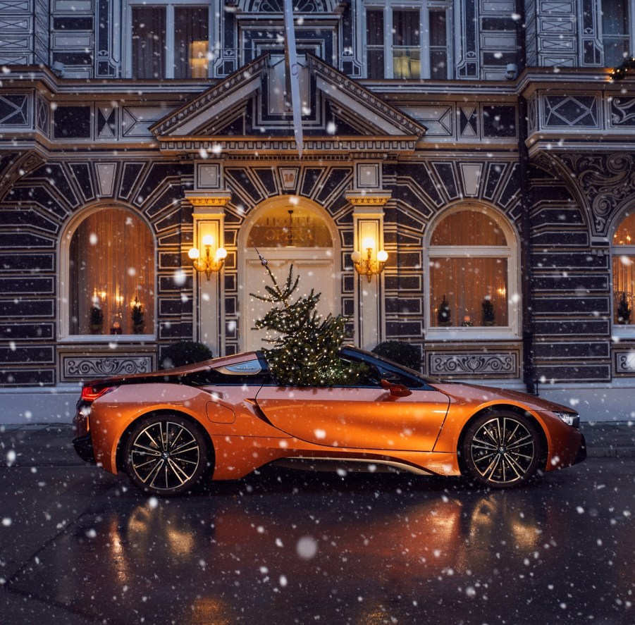 An orange BMW i8 Roadster with a Christmas tree in the passenger seat