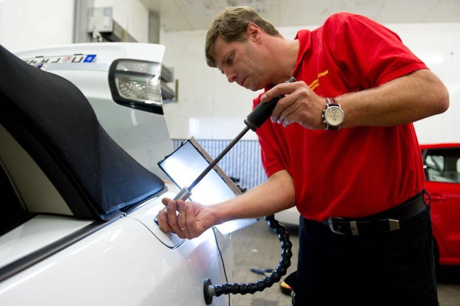 A PDR specialist removes dents from the panels on a car