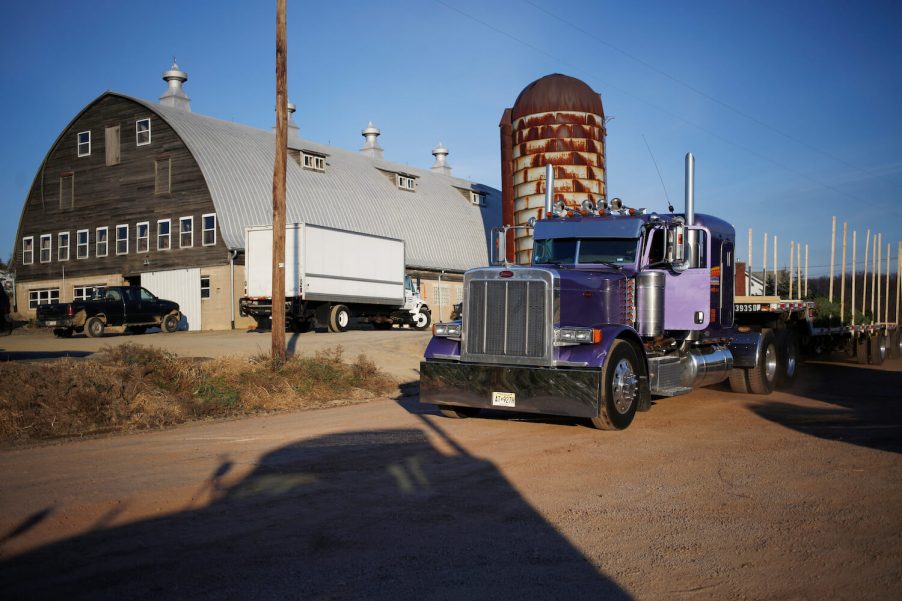 A semi-truck with Pennsylvania plates parked in front of a barn and silo.