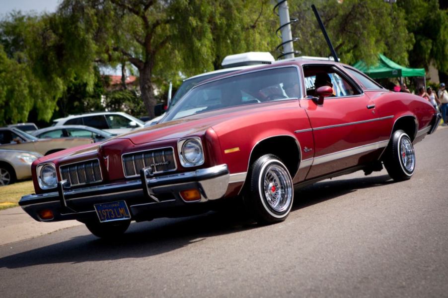 A Pontiac Le Mans driving in a parking lot.