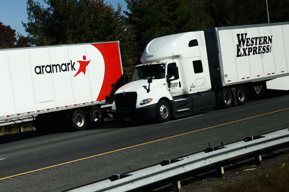 Two semi-trucks towing trailers cruise down a highway.