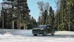 A 2023 Subaru Forester sits in a snowy forest. The Forester has one of the lowest projected cost of ownership ratings of any compact SUV.