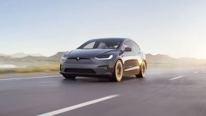 A gray Tesla Model X EV adds mileage blasting down a desert road.