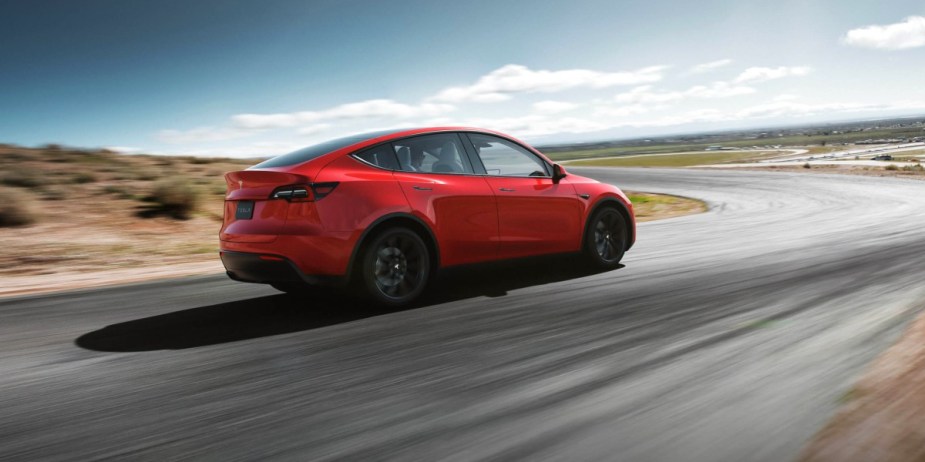 A red 2023 Tesla Model Y is driving on the road. 