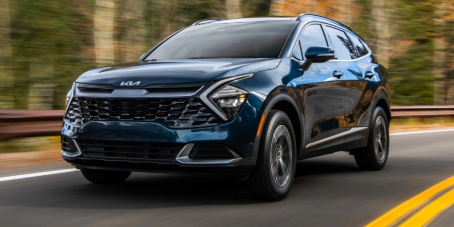 A blue 2023 Kia Sportage Hybrid small hybrid SUV is driving on the road.