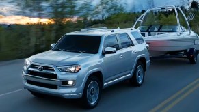 A gray 2023 Toyota 4Runner midsize SUV is towing a boat on the road.