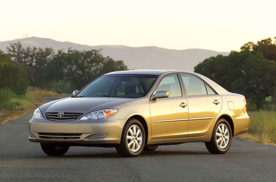 A gold Toyota Camry parked on a single lane road at sunset