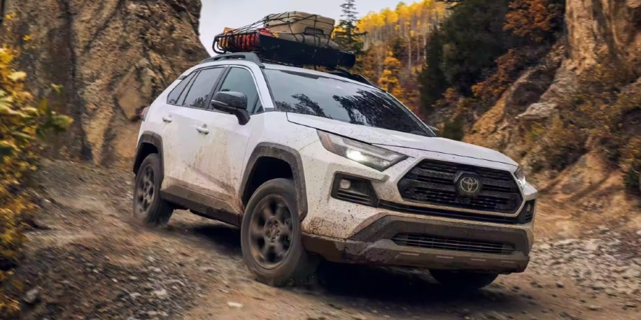 A white 2023 Toyota RAV4 small SUV is driving off-road. 