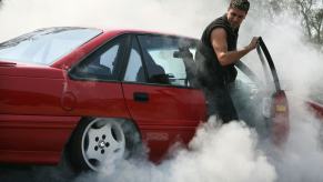 A car enthusiast does a burnout in an old Ford Focus