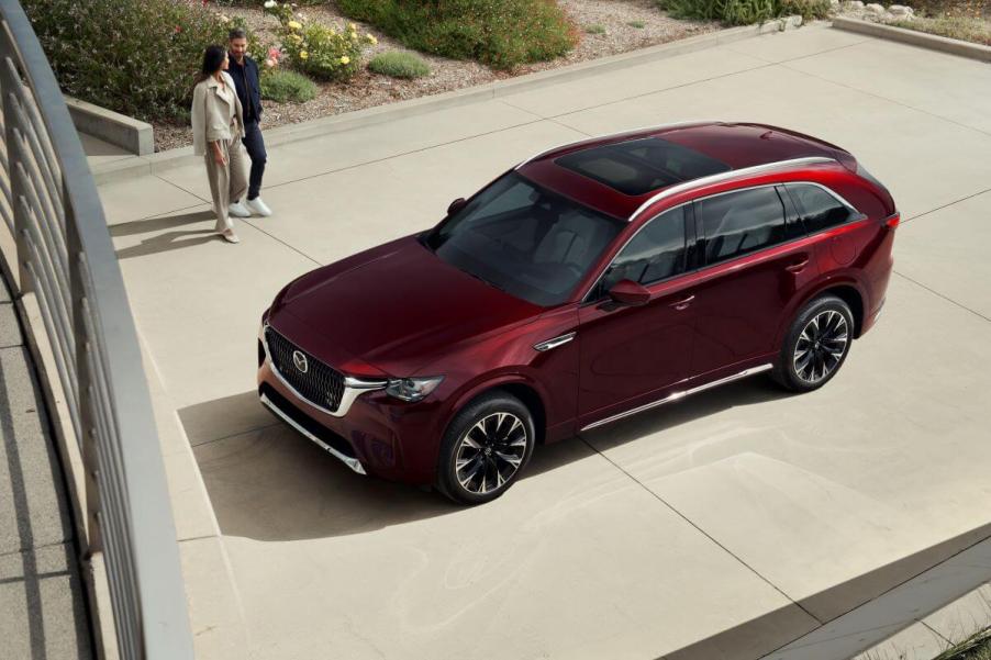 An overhead shot of a red 2024 Mazda CX-90 full-size SUV model with a couple walking toward it