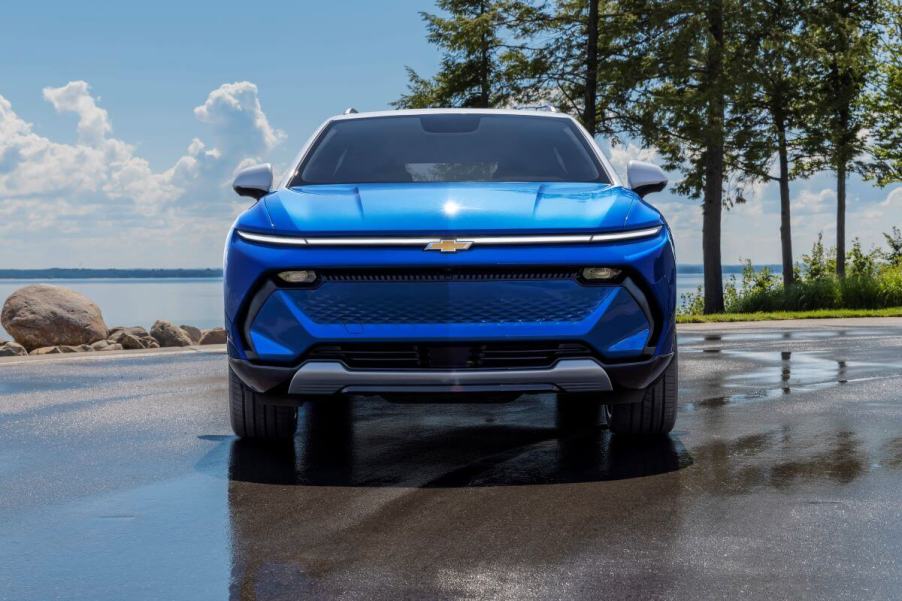 A blue 2024 Chevy Equinox EV 3LT compact electric SUV model parked on wet pavement near water