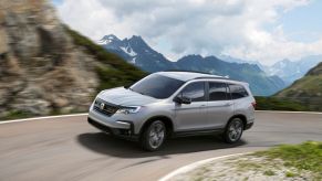 A gray 2022 Honda Pilot Sport midsize SUV model driving on a mountain highway