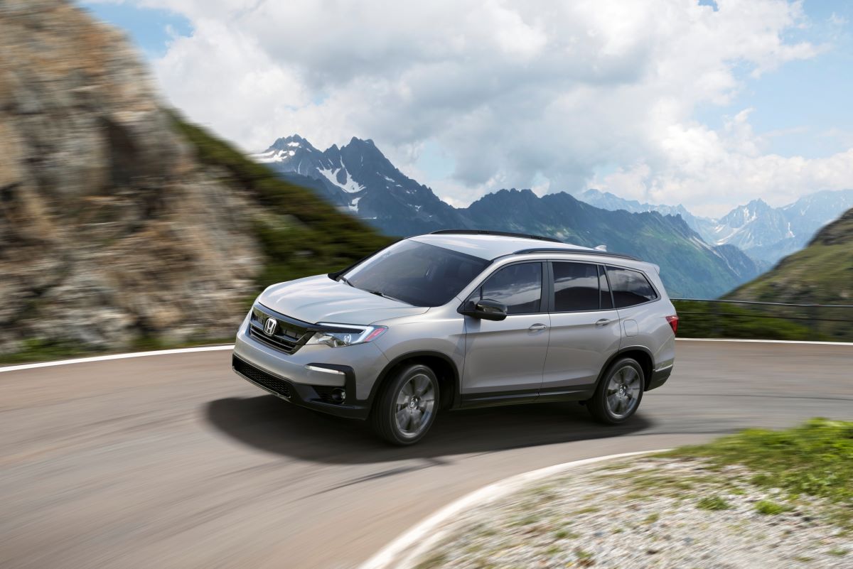 A gray 2022 Honda Pilot Sport midsize SUV model driving on a mountain highway