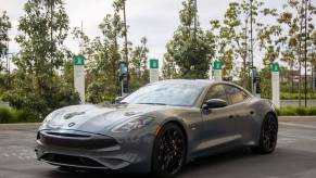 A Karma GS-6 hybrid executive sedan/luxury car model parked near a row of electric vehicle (EV) charging stations