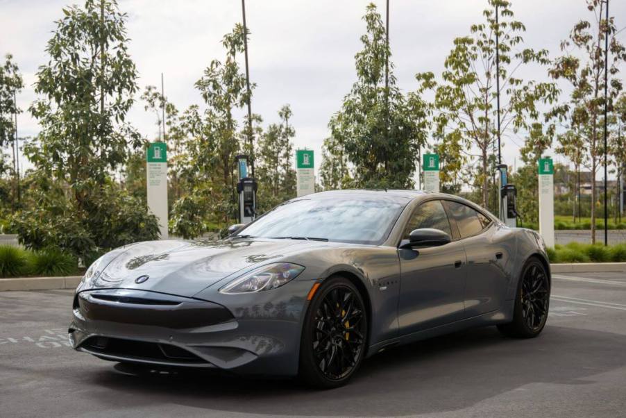 A Karma GS-6 hybrid executive sedan/luxury car model parked near a row of electric vehicle (EV) charging stations