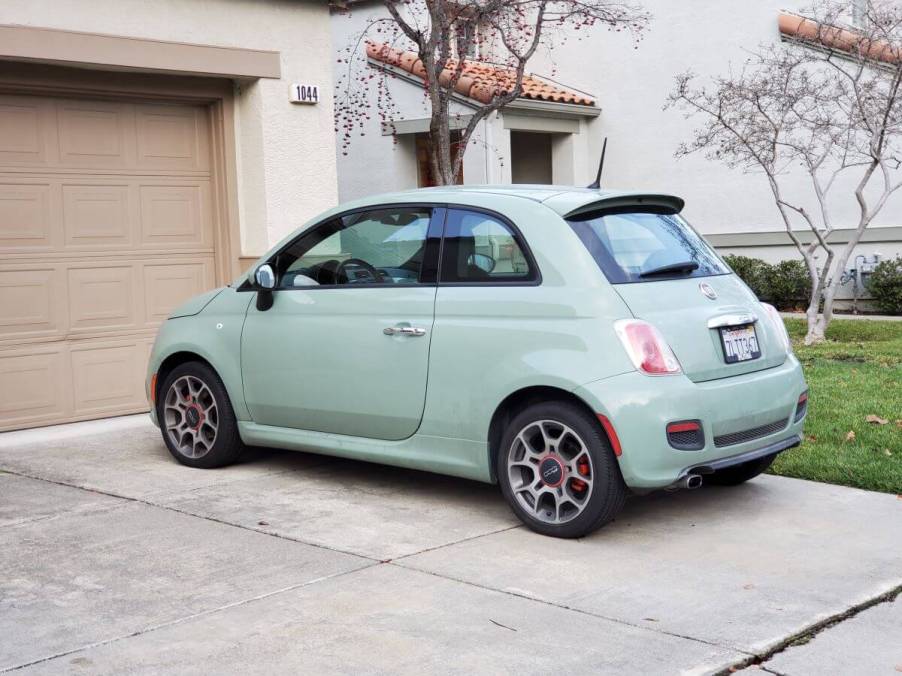 A mint green Fiat 500 model parked on a driveway outside a suburban home garage in San Ramon, California