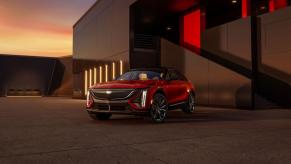 A red 2024 Cadillac Lyriq electric full-size luxury SUV model parked outside a luxury building at sunset