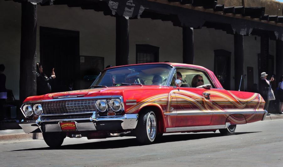 A red customized 1962 Chevy Impala lowrider model driving in a parade in Santa Fe, New Mexico