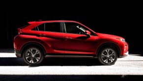 A side profile shot of a red 2019 Mitsubishi Eclipse Cross compact SUV model cloaked in shadows. This is a popular used Mitsubishi model