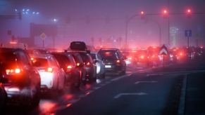 Bumper-to-bumper traffic waits on the interstate, tail lights illuminating the fog.