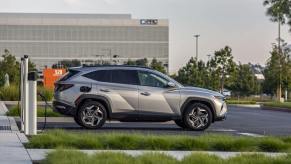 A side profile shot of a 2023 Hyundai Tucson Plug-In Hybrid compact SUV model parked into an EV charging station