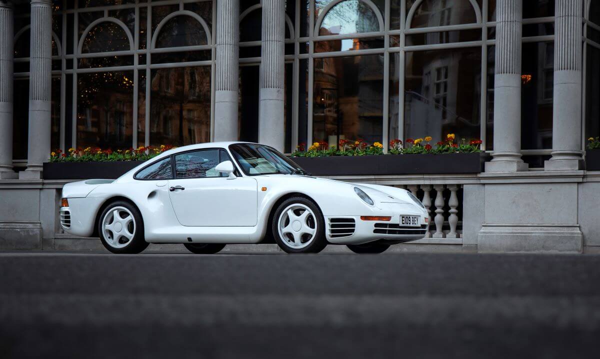 A white Porsche 959 sports car coupe rally model parked in front of the Connaught Hotel in Mayfair, London