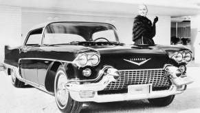 A smiling woman stands beside a 1957 Cadillac Eldorado Brougham