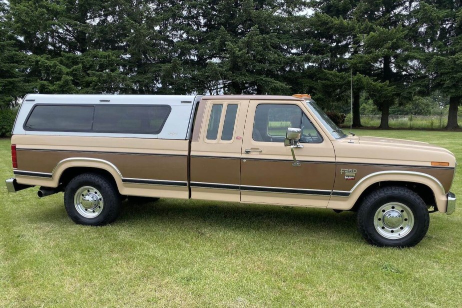 A seventh-generation Ford truck in two-tone brown and cream paint parked on a lawn, trees in the background.