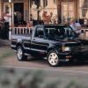 A 1991 1991 GMC Syclone half-ton pickup truck model parked on gravel outside a patio shop