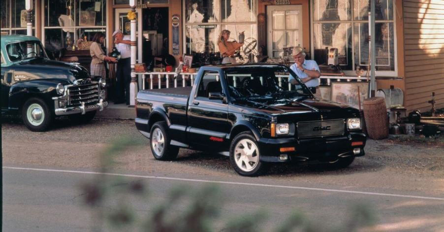 A 1991 1991 GMC Syclone half-ton pickup truck model parked on gravel outside a patio shop