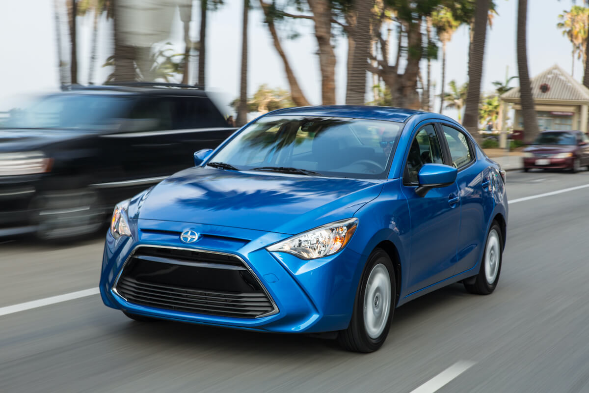 A blue 2016 Scion IA driving down a street