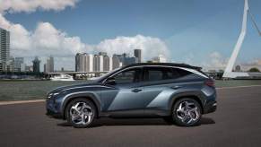 A steel-blue 2018 Hyundai Tucson overlooks water and a city skyline