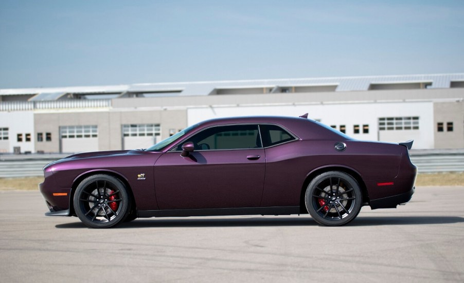 A purple Dodge Challenger R/T Scat Pack 1320 poses next to a drag strip.