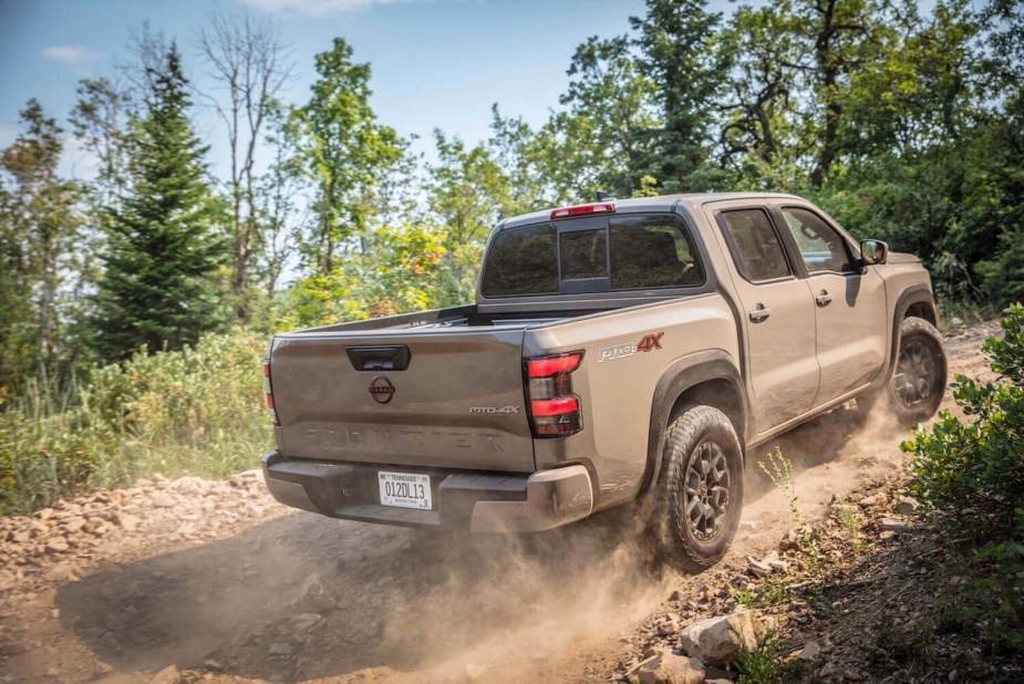 A tan Nissan Frontier climbs an off-road trail.