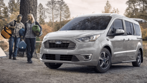 A gray 2023 Ford Transit Connect compact panel van commercial vehicle parked near a forest river during a camping trip