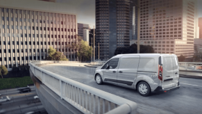 A white 2023 Ford Transit Connect compact panel van commercial vehicle driving on a city highway overpass