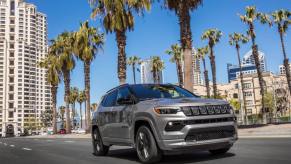 A 2023 Jeep Compass High Altitude compact SUV model driving under palm trees