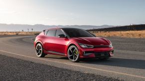 A red 2023 Kia EV6 GT compact SUV model parked on the side of a desert highway road