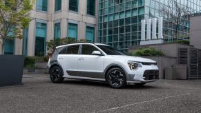 A white 2023 Kia Niro EV driving on a city street.