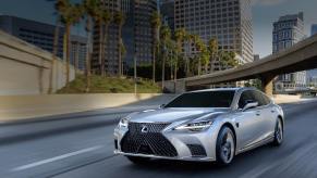 A 2023 Lexus LS 500h driving down a road.